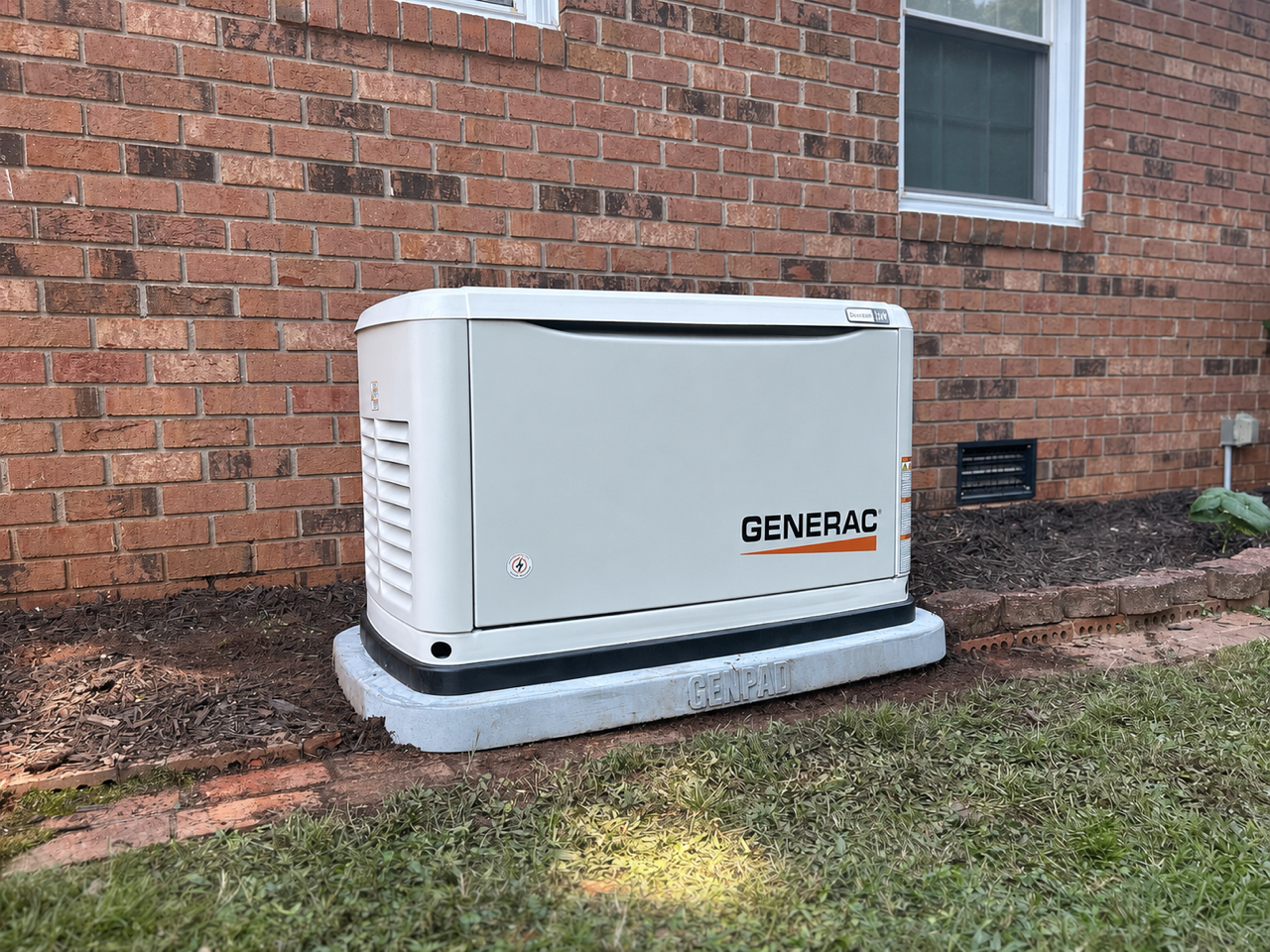 Generac generator on a GenPad concrete pad beside a brick Upstate SC home