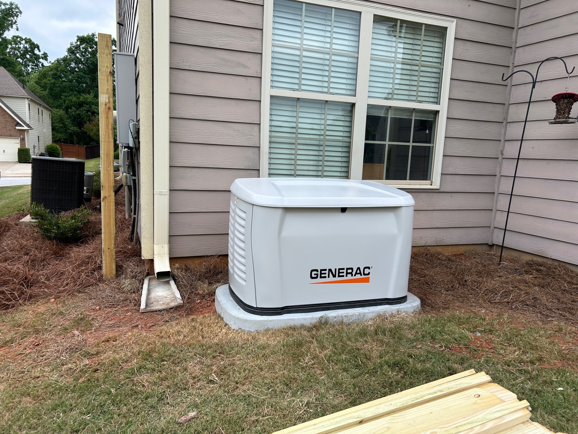 Generac standby generator installed beside an Upstate SC home with bird feeder and landscaping